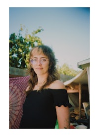 a woman with glasses standing in front of a tent